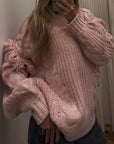 Person wearing a pink knitted sweater taking a mirror selfie.